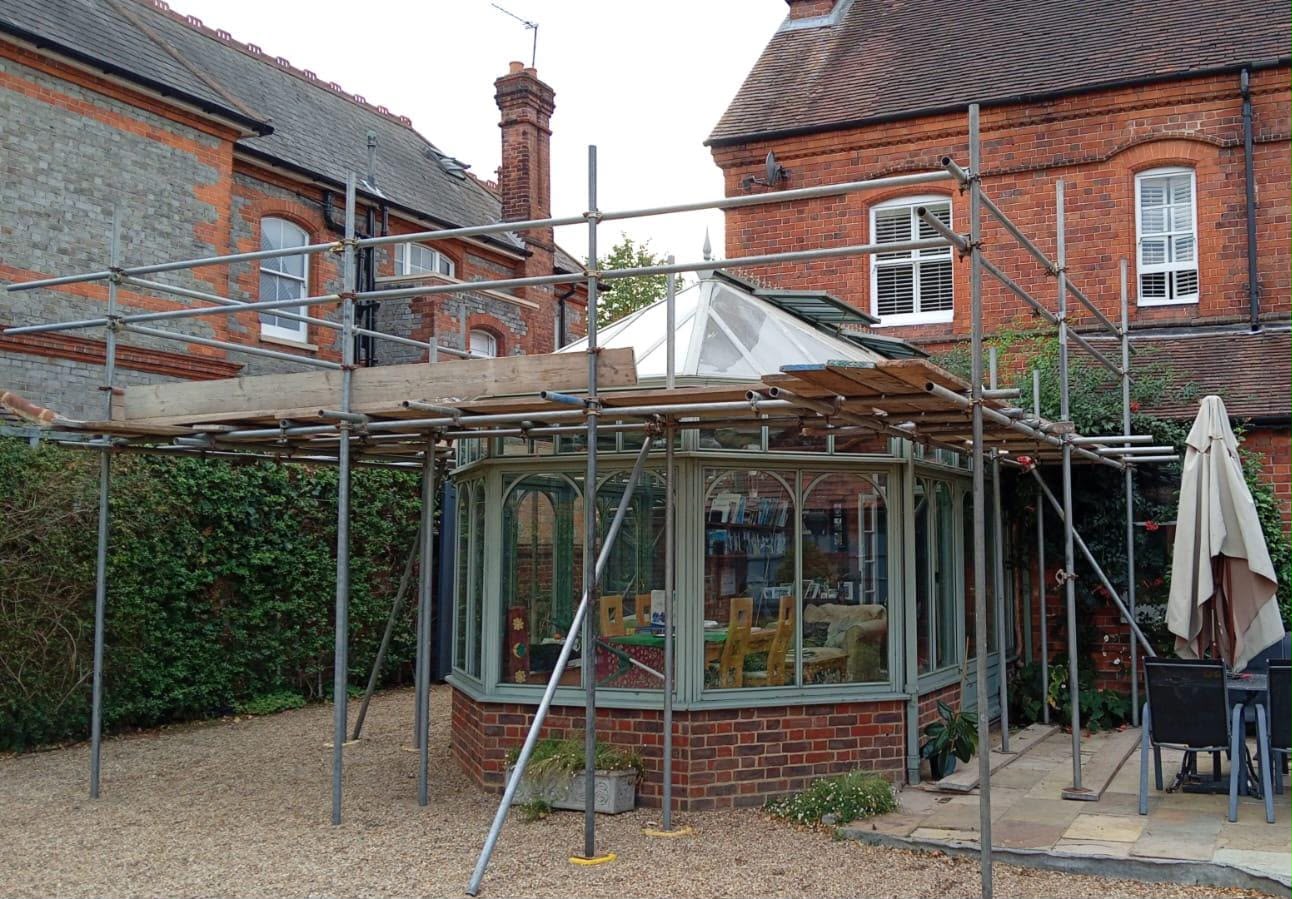 Conservatory before restoration, scaffolding in place and original frame colour